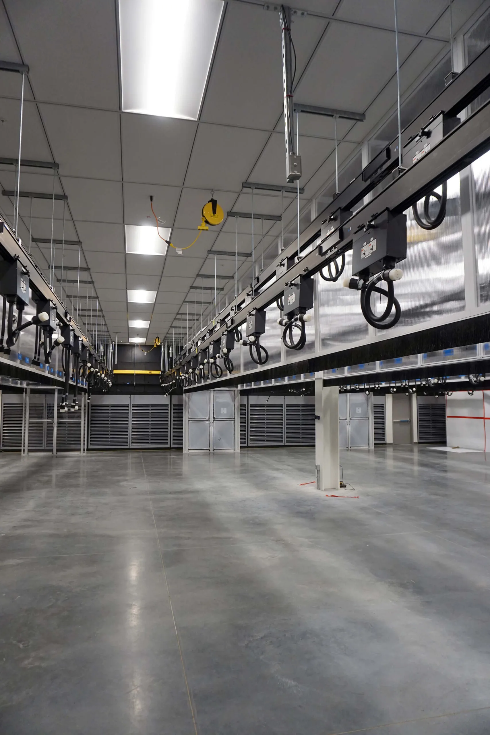 A large empty industrial warehouse with overhead conveyor systems and polished concrete floors, perfect for commercial construction projects.