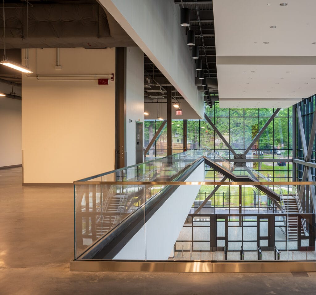 Data Center Work 9 The modern interior, perfect for a data center workspace, features glass railings, concrete floors, and large windows overlooking a lush green area.